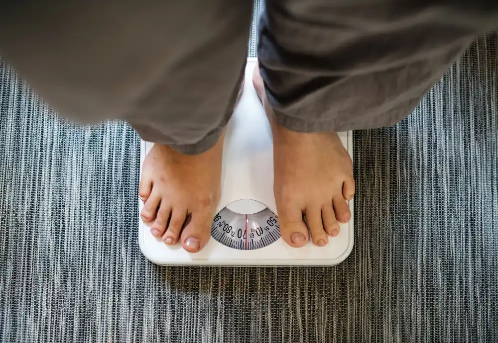 Individual checking their weight on a scale during a weight loss journey