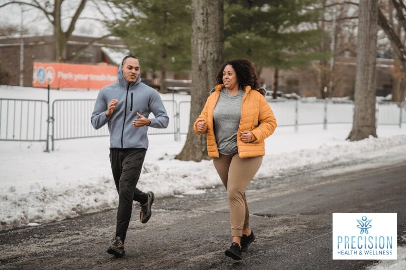 Woman in orange jacket running with a fit man in cold weather to support hormone balance and weight loss
