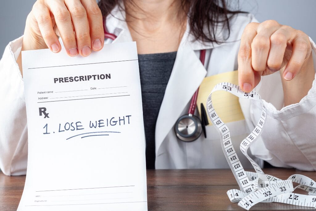 Doctor holding weight loss prescription and measuring tape
