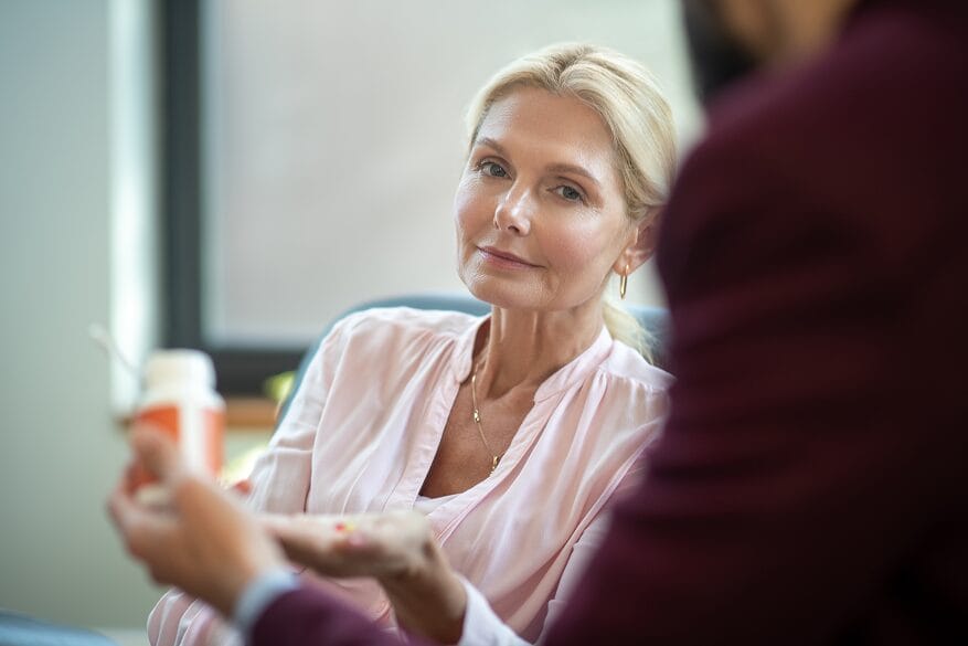 Woman discussing hormone replacement therapy with her doctor during menopause consultation
